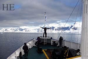 a man feeling like he's king of the world in the front of the vessel in antarctica