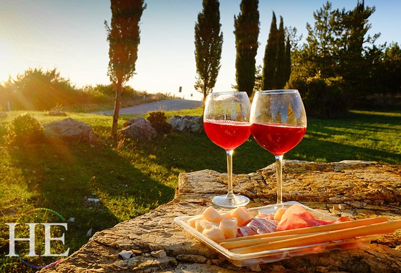 plate of cheese and glasses of wine gleaming in a tuscan sunset