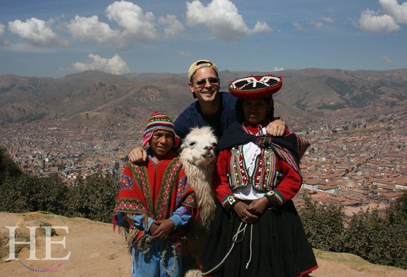 A traveler, two locals and a llama pose for a picture on HE Travel's Gay Machu Picchu Luxury Tour in Peru.