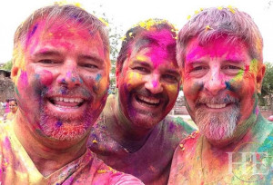 closeup of three guys spattered with multicolored powders at holi festival on the HE Travel gay India Adventure tour