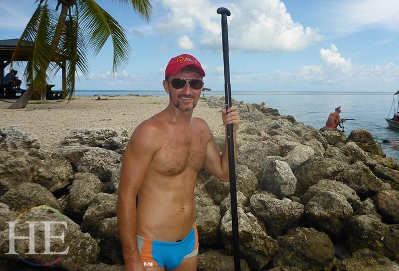 zach moses poses with a kayak paddle on a rocky beach in the florida keys