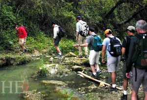 a group of men crosses a creek on the HE Travel gay hiking tour in Tuscany Italy