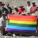 holding a gay pride rainbow flag at olduvai gorge on the HE Travel gay Tanzania Africa safari