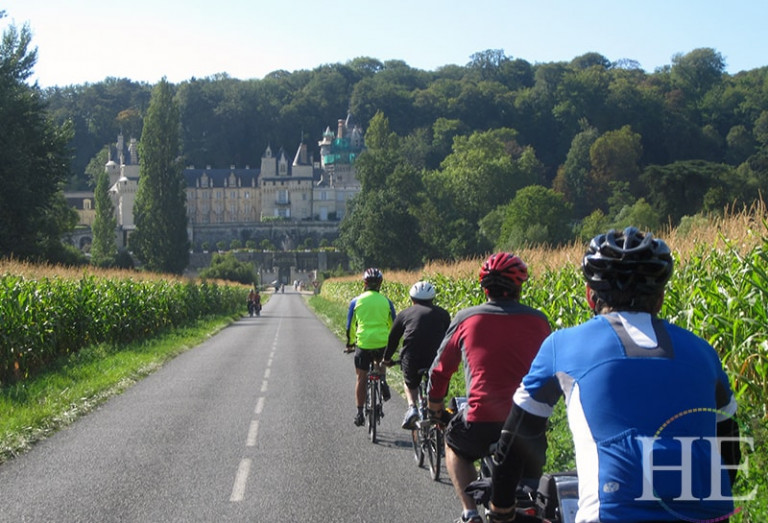 Travelers cycling toward a castle on HE Travel's Valley of the Chateaux Tour.