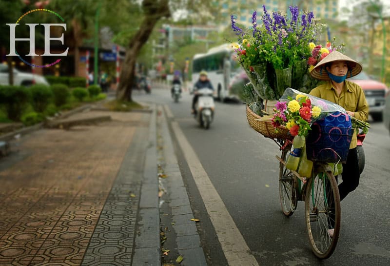 a flower seller pushes a bike on the HE Travel gay tour of Vietnam and Cambodia