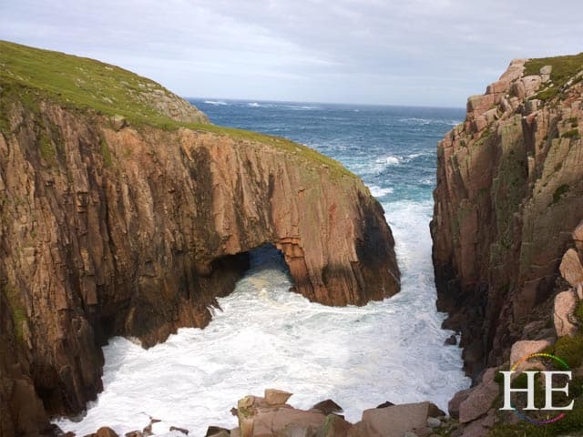 Waves crash through an ocean arch on Gola Island in Ireland.