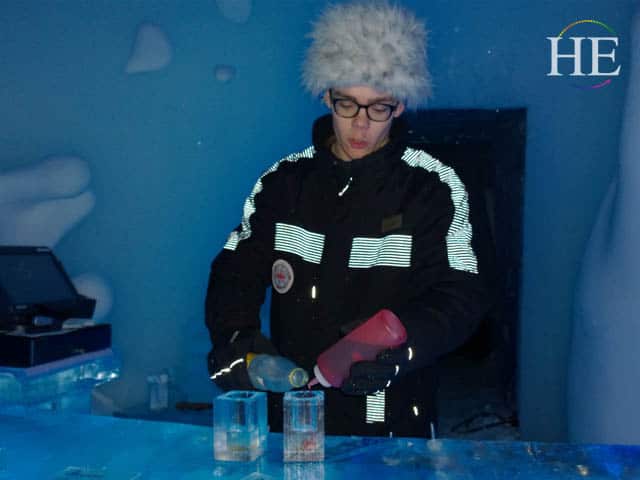 bartender pours drinks into ice galsses at the ice hotel in sweden