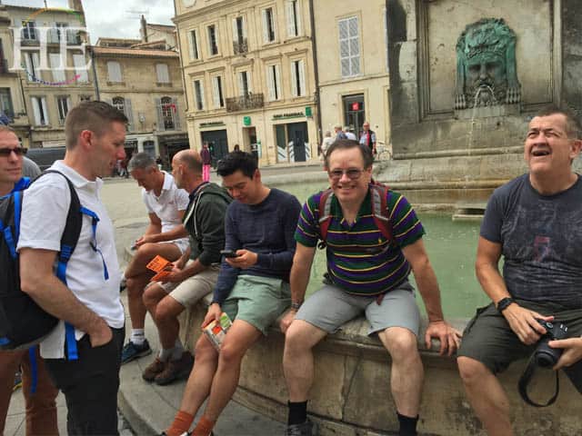 a group of men sitting on a fountain edge in arles