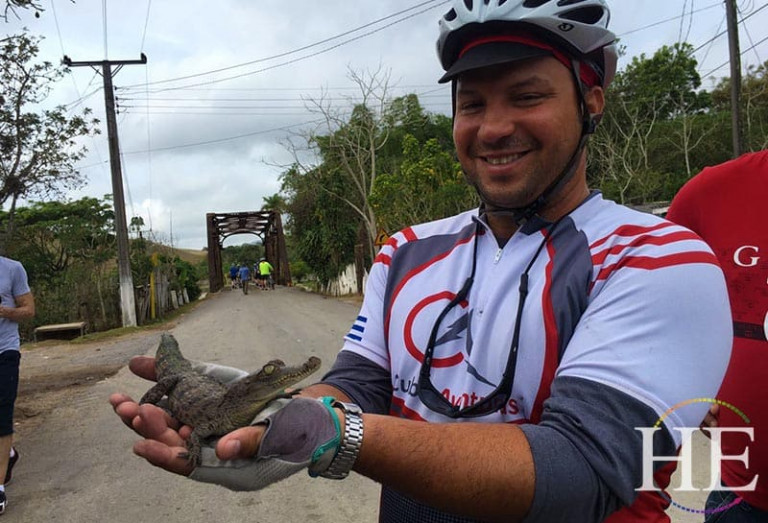 a cyclist holds an alligator in cuba