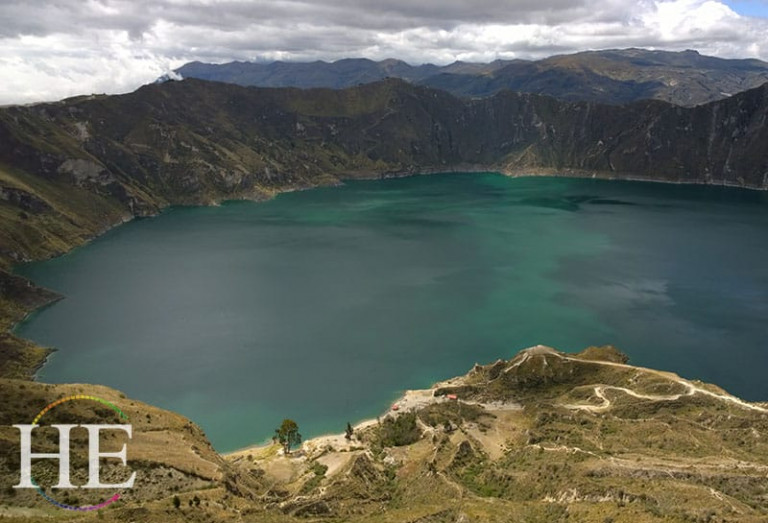Peering down into emerald water of quilotoa crater on the HE Travel gay Ecuador adventure