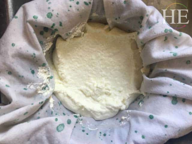 curds straining in a cotton linen lined colander to create ricotta