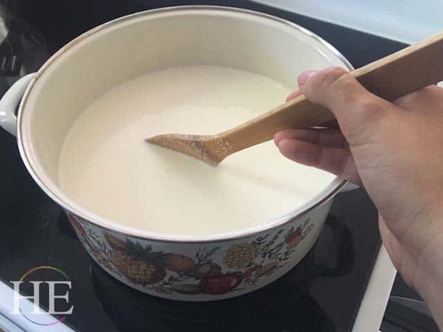 stirring a pot of hot milk to make ricotta cheese