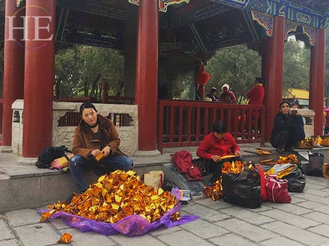 visitors fold gold fortune papers at a park in zhengzhou china