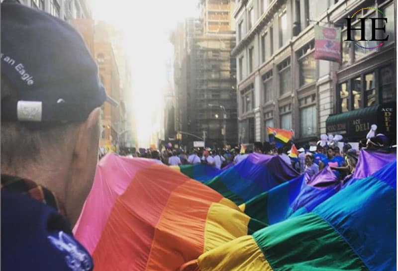 A photo of Phillip Sheldon carrying a rainbow flag for stonewall 50th anniversary