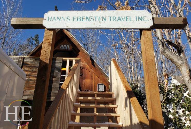 Vintage sign reading Hanns Ebensten Travel Inc. is mounted above a new wooden stair case