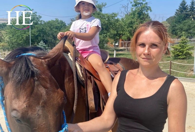 masha stands with her horse and a child