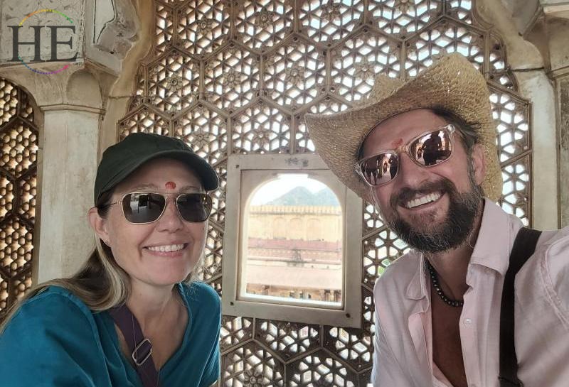Zachary Moses and Trisha Moses pose on either side of an opening in a palace wall in India