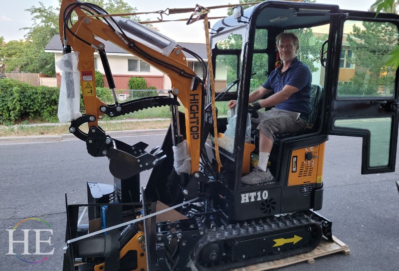 Eric Moses sits in a yellow excavator that he unloaded